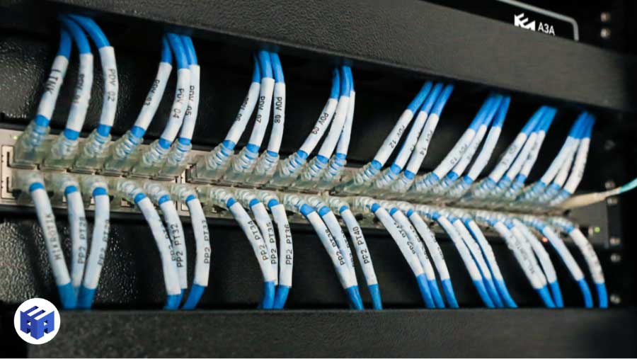 Rack de cabeamento estruturado em detalhe com cabos de rede azuis organizados, identificados com etiquetas, em infraestrutura de TI profissional.