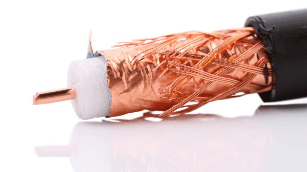 Close-up de cabo coaxial com blindagem de cobre, usado em redes de dados e sistemas de comunicação, mostrando a estrutura interna de isolamento e malha de proteção.
